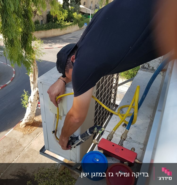טכנאי מתקין מזגן עם צינורות וכלים על גג